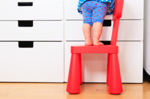 kids safety concept- little girl climbing on baby chair